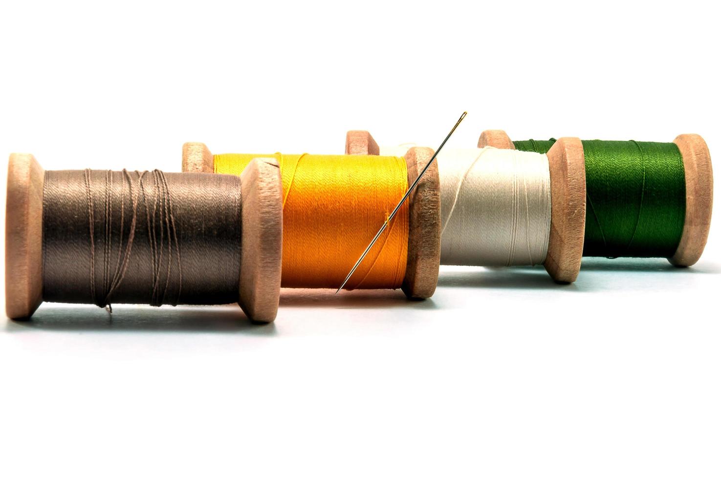 Isolated wooden spools of thread with a needle photo