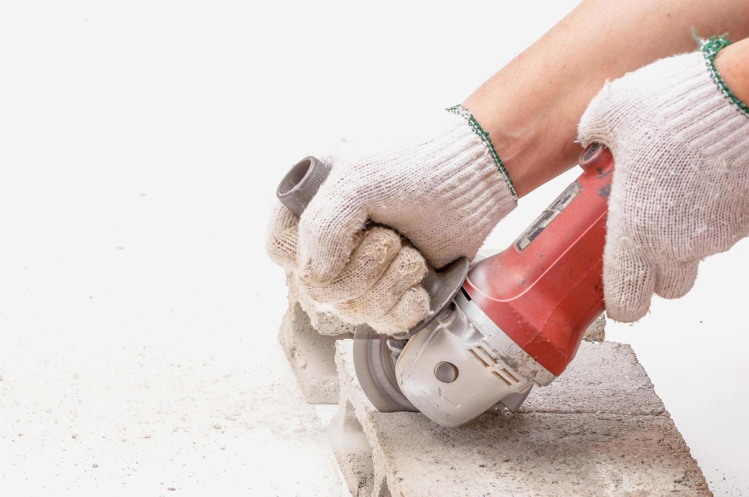Worker is using angle grinder for cutting cement block, hand tool, focus at blade and isolated over white. photo