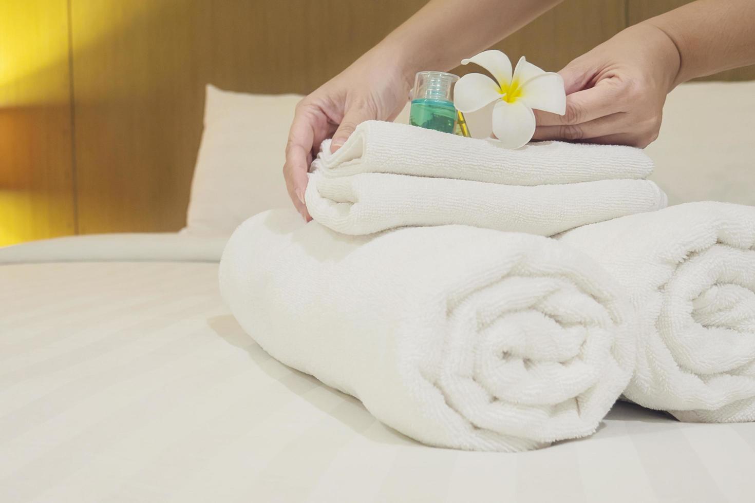 Lady set up white towel set on bed in hotel room photo