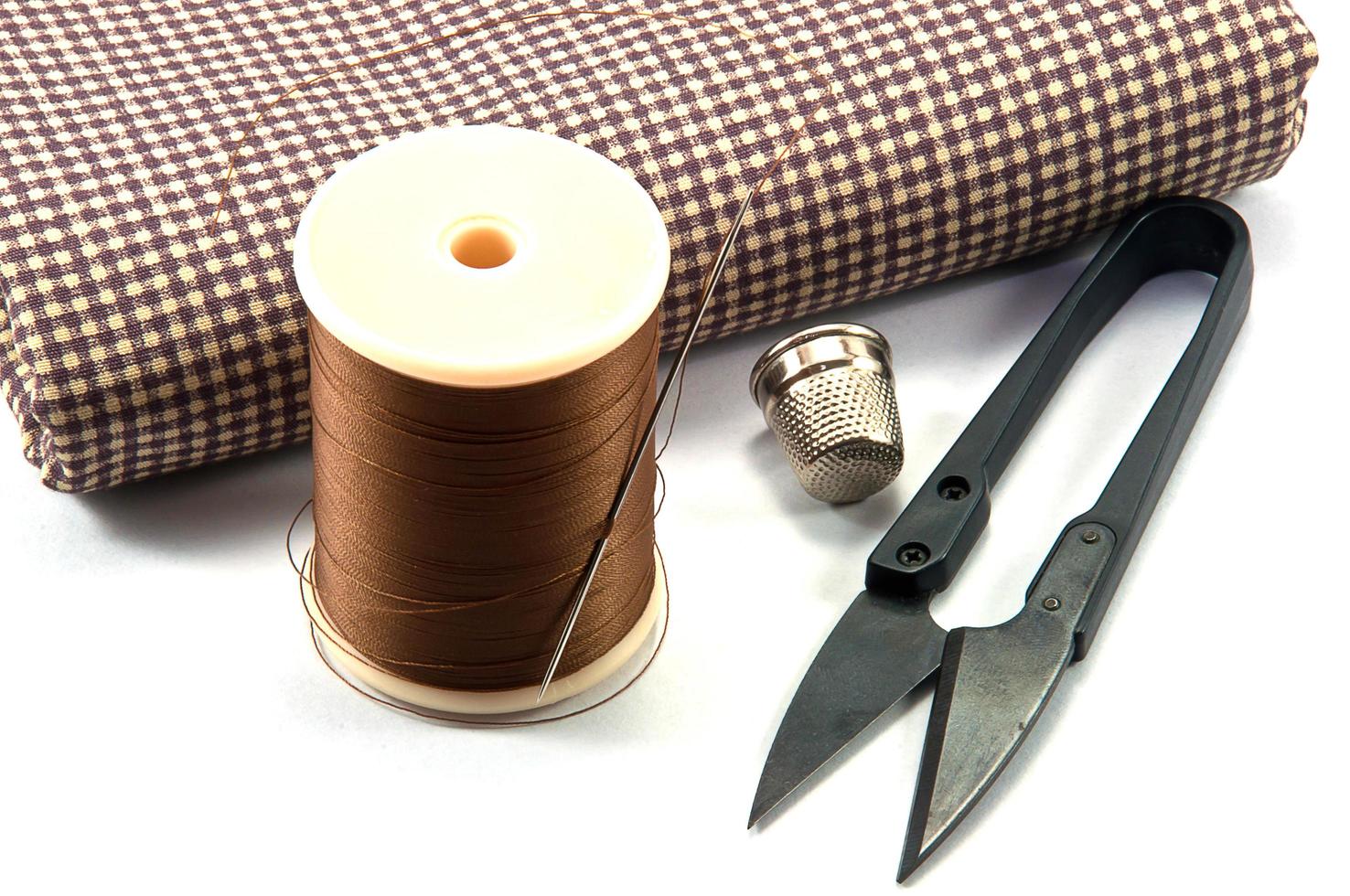 Thimble,needle,spools and scissor with cloth for sewing on white background photo