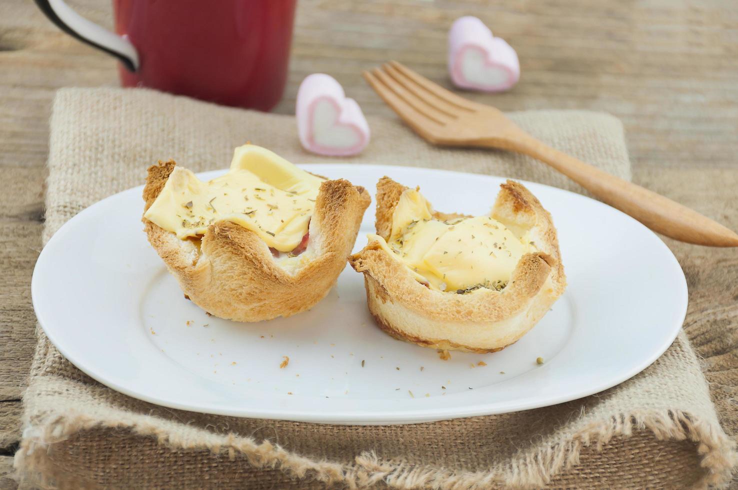 Egg cheese bread toast on white dish with wooden fork and red coffee mug and heart marshmallow background photo