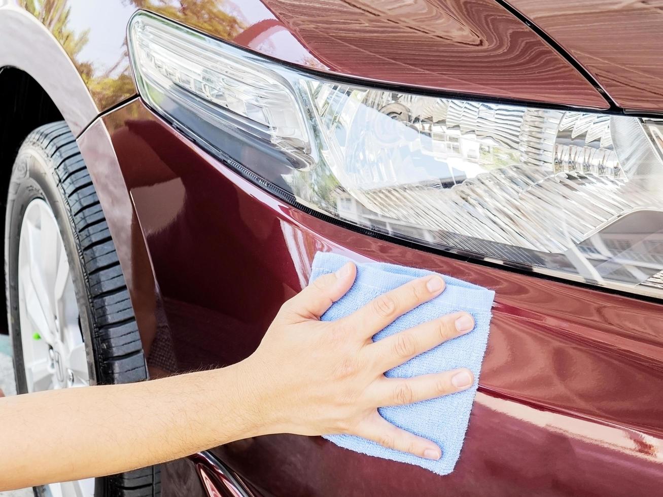 Man's hand is cleaning and waxing the car photo