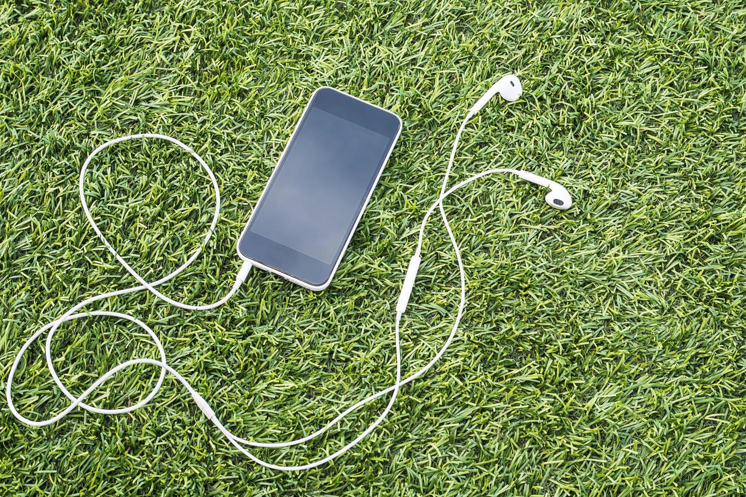 Mobile phone with head phone on green artificial grass photo