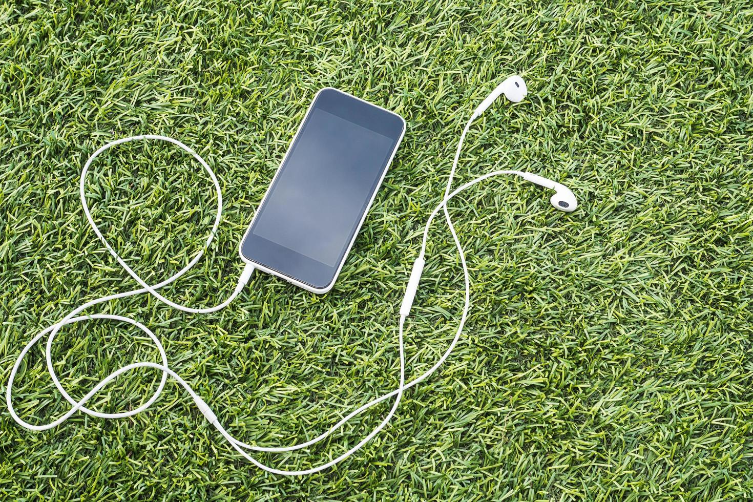 Mobile phone with head phone on green artificial grass photo