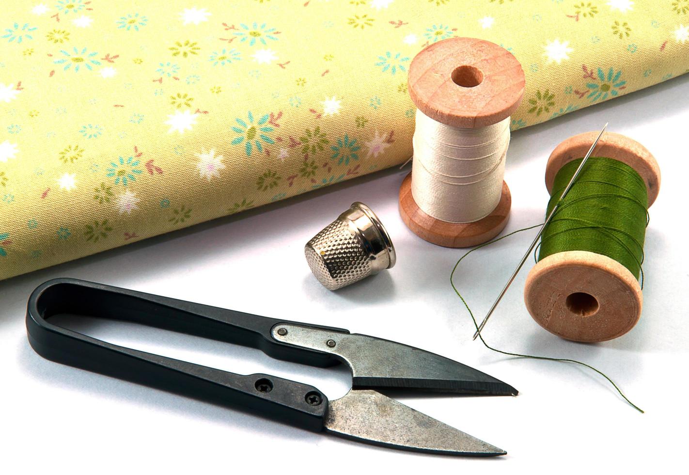 Thimble,needle,spools and scissor with cloth for sewing on white background photo