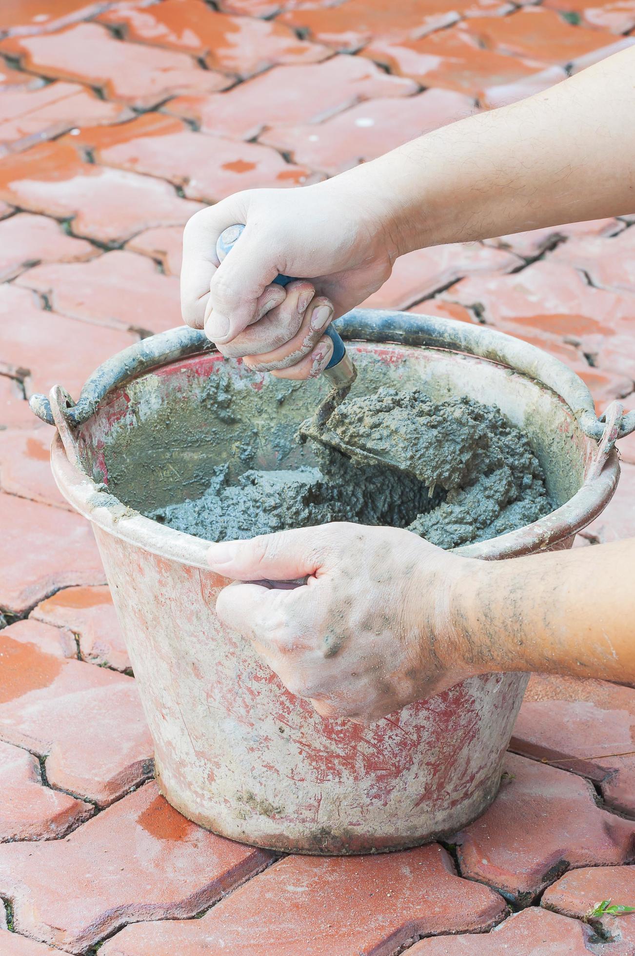 Hand holding trowel mixing mortar in a bucket 8415066 Stock Photo at