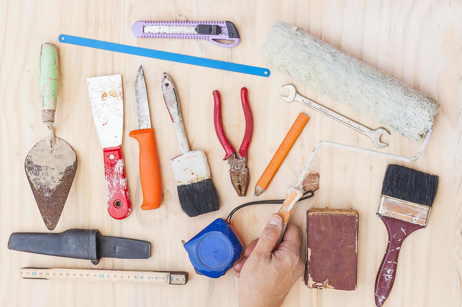 Old construction hand tool set with worker hand over white wooden background photo