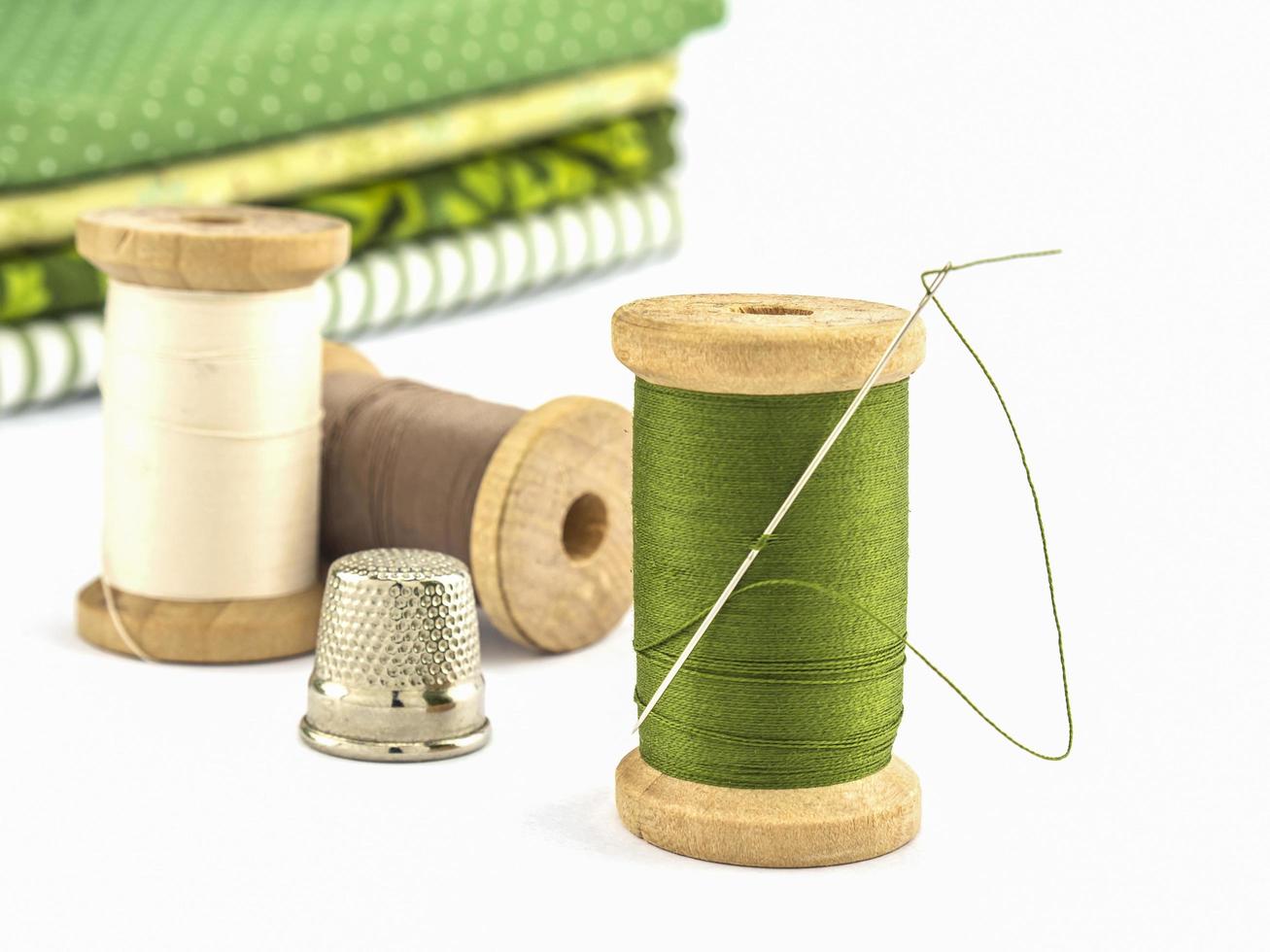 Wooden spool of thread embroidery set with cloth over white background photo