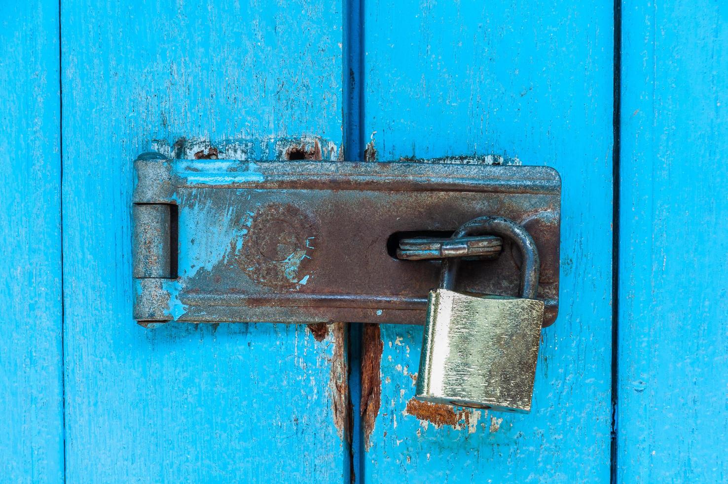 Old blue wooden door with rusty padlock and lock for background use photo