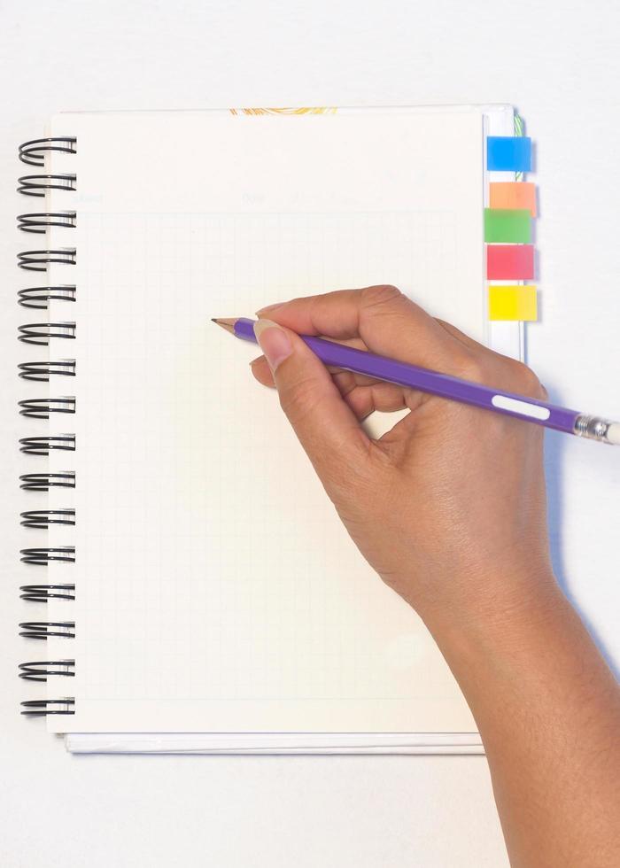 Lady's hand holding pencil ready to write an empty notebook with sticky note memo photo