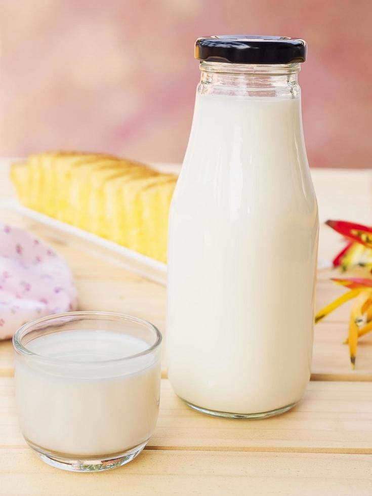 Bottle with glass of milk and butter cake on white wooden table. photo