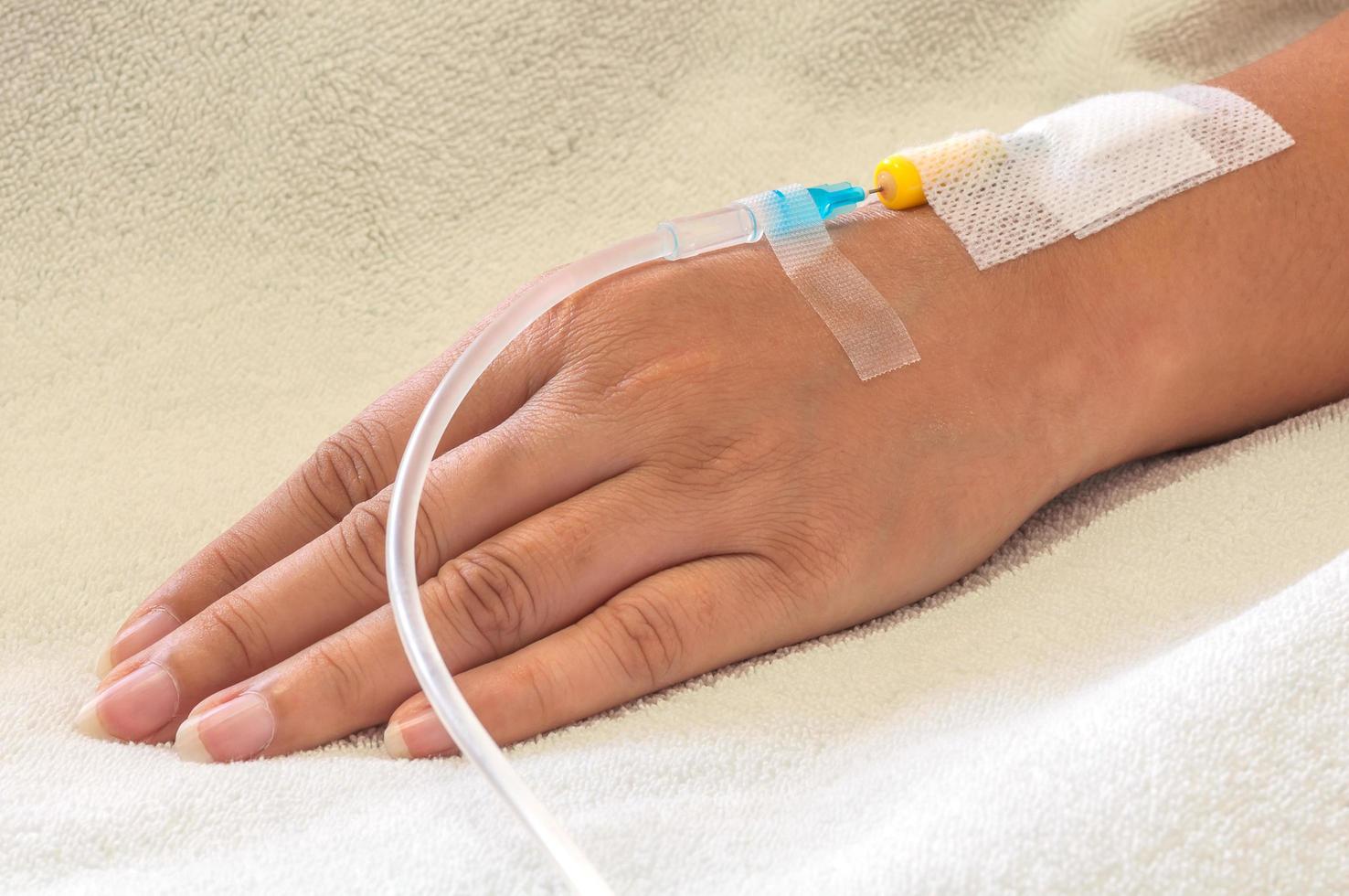 Patient's hand with medicine drip injection, lady on a bed in a hospital photo