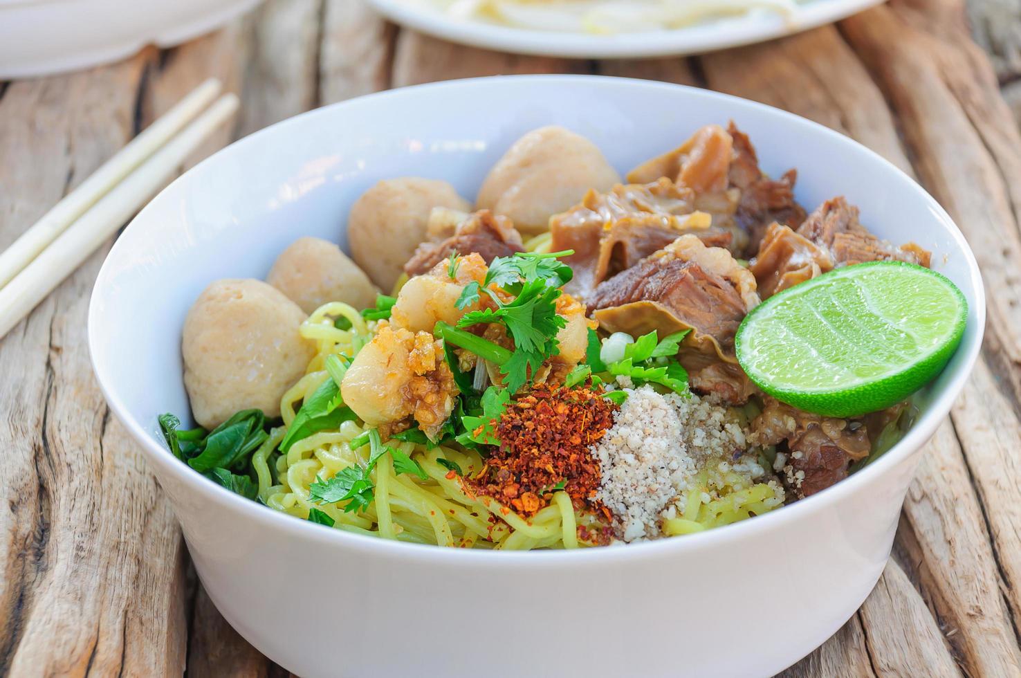 Thai - Chinese style spicy noodle with steamed pork and pork ball served with fresh vegetable and soup photo