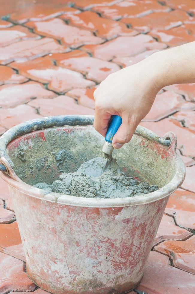 Hand holding trowel mixing mortar in a bucket photo