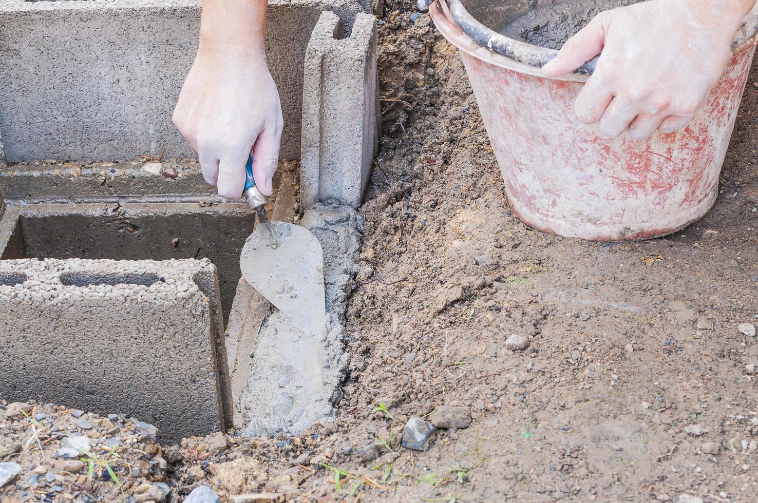 Construction worker is working with cement block on site installation. Manhole cover of housing drainage pipe installation. photo