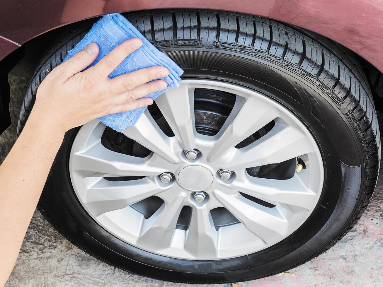 A man's hand is cleaning and waxing tire of car photo