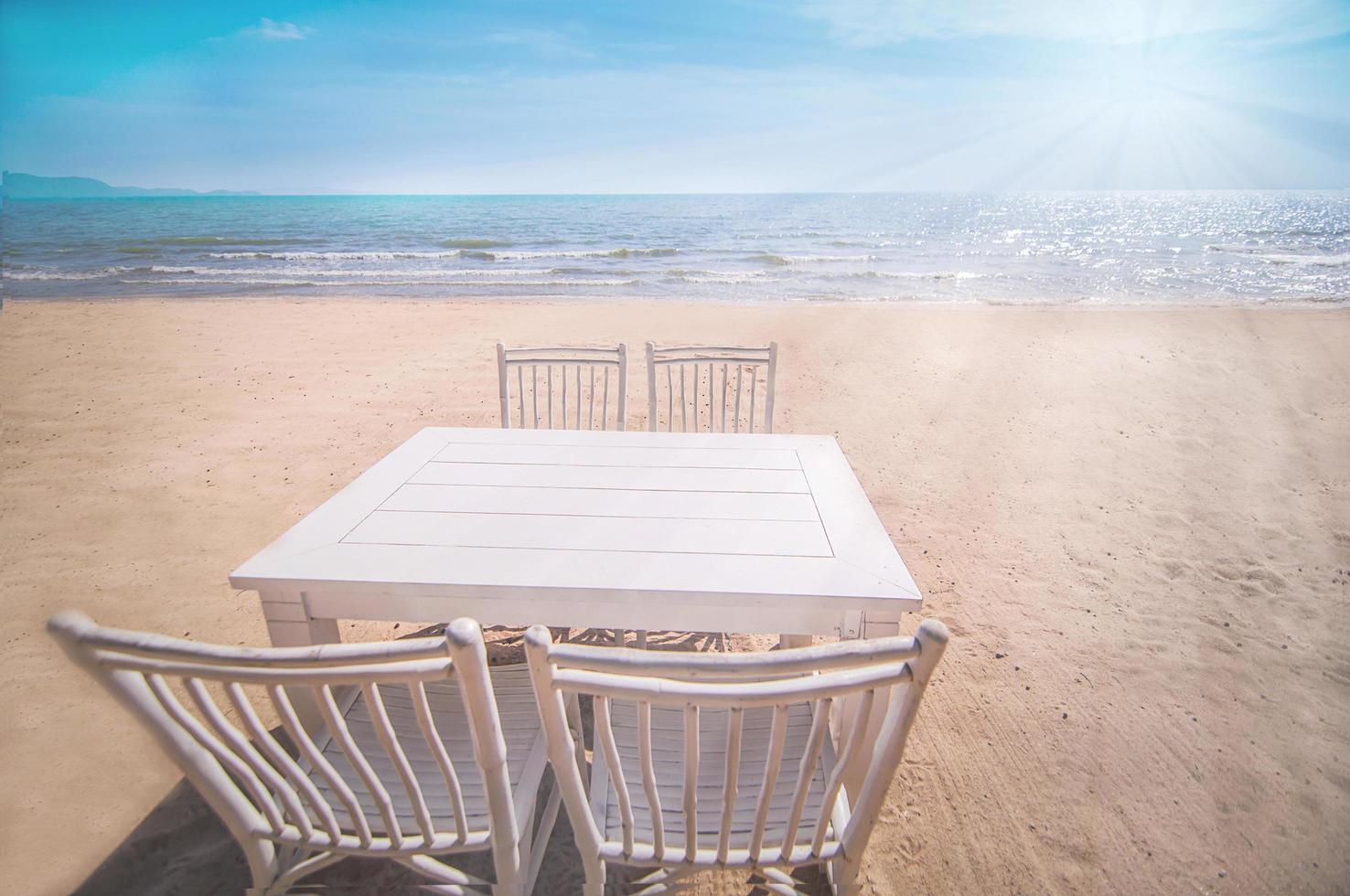 conjunto blanco de sillas relajantes y mesa en la playa de pataya, tailandia con cielo azul y fondo de luz solar foto