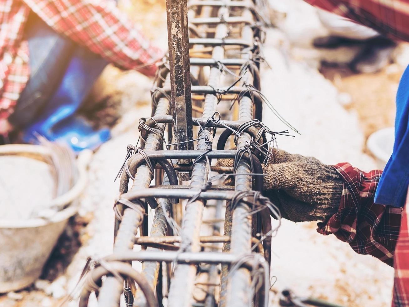 Vintage style photo of construction workers are installing steel rods in reinforced concrete beam