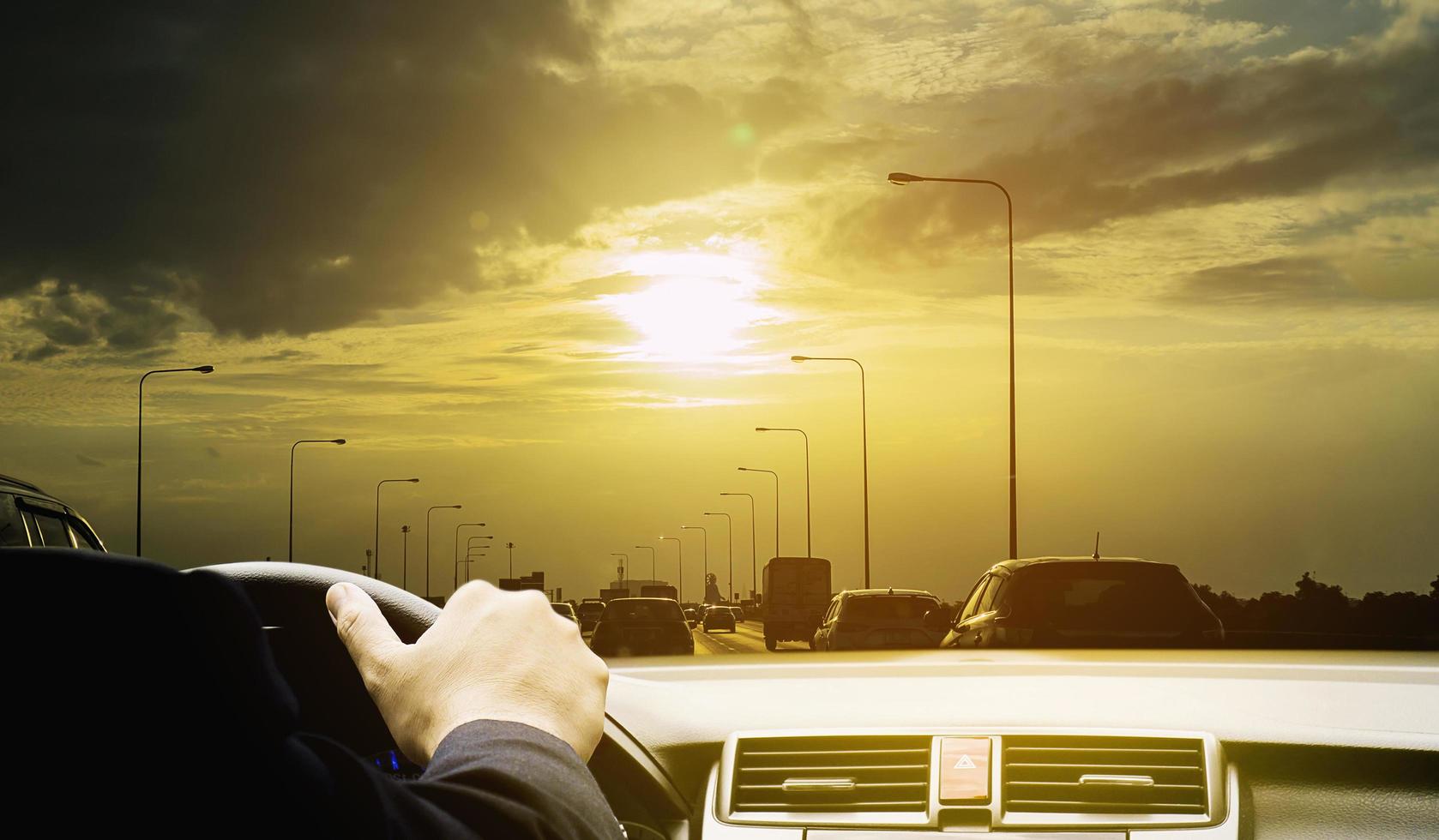 Man is driving a car on sunny day with golden sky and cloud background photo
