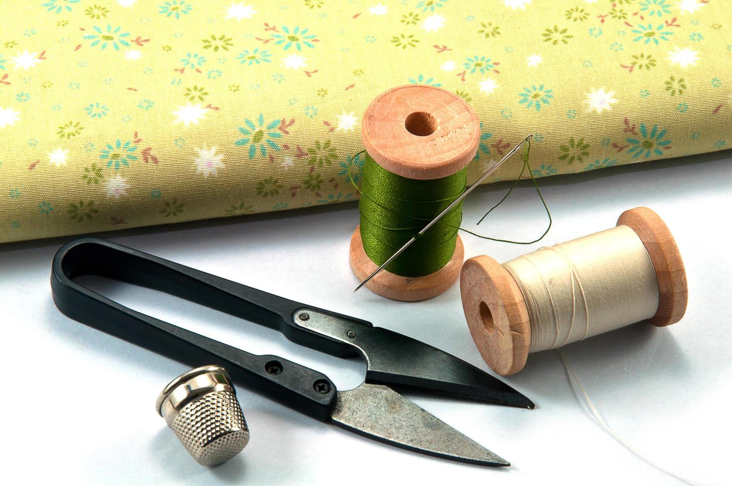 Thimble,needle,spools and scissor with cloth for sewing on white background photo