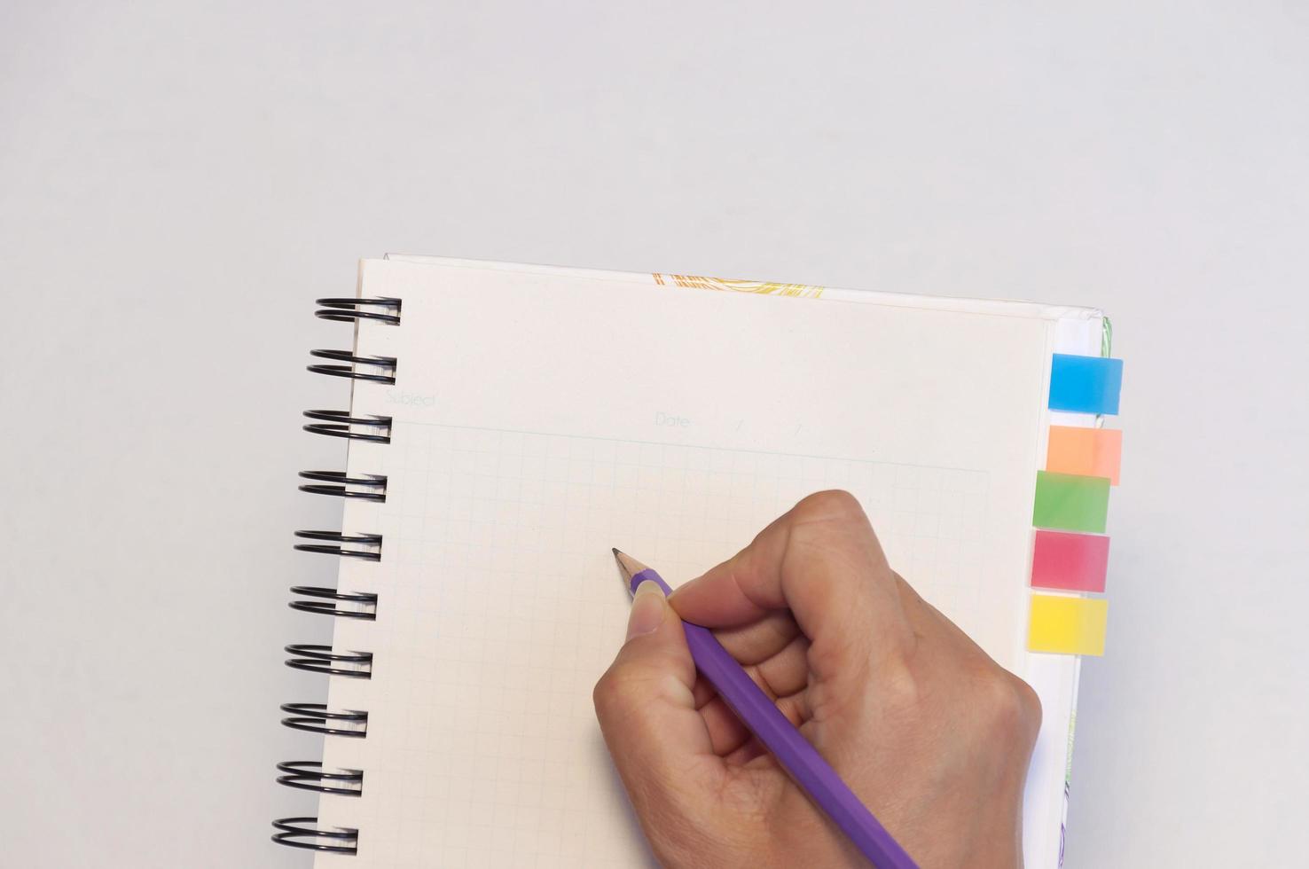 Lady's hand holding pencil ready to write an empty notebook with sticky note memo photo