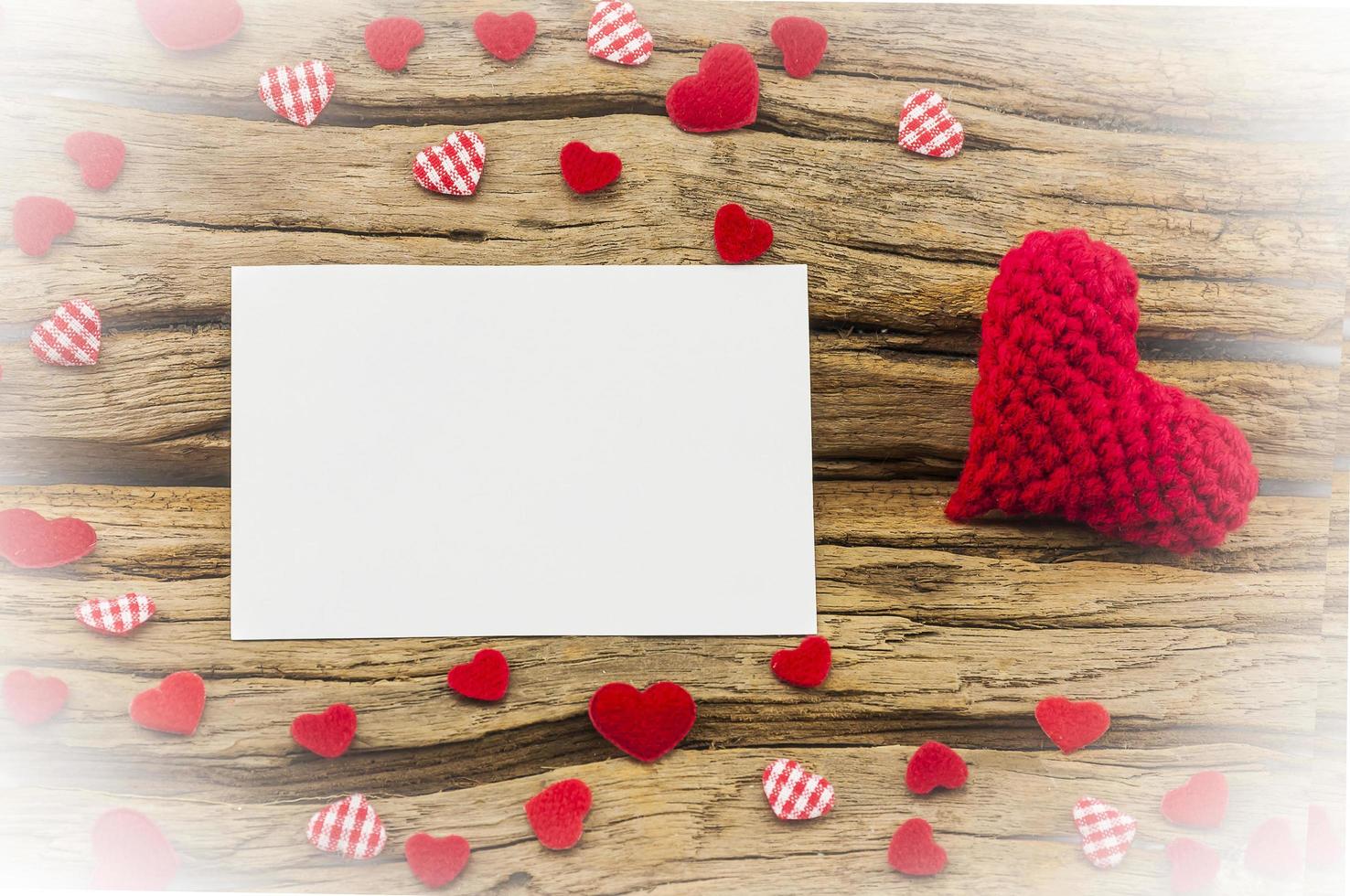 Small red hearts and empty white card putting on wooden background photo