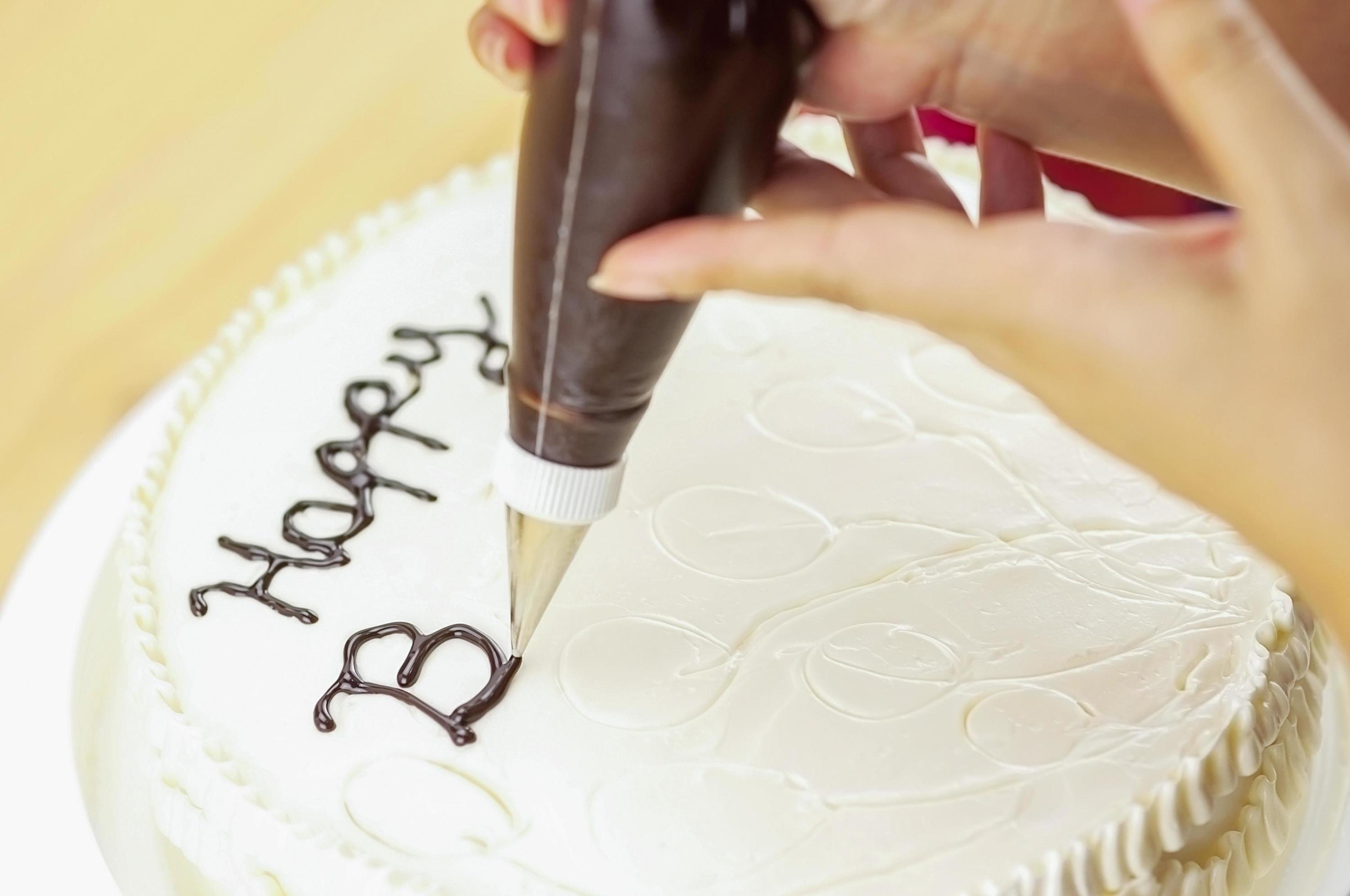 Cake decorating using piping tip for writing a word 8416570 Stock Photo