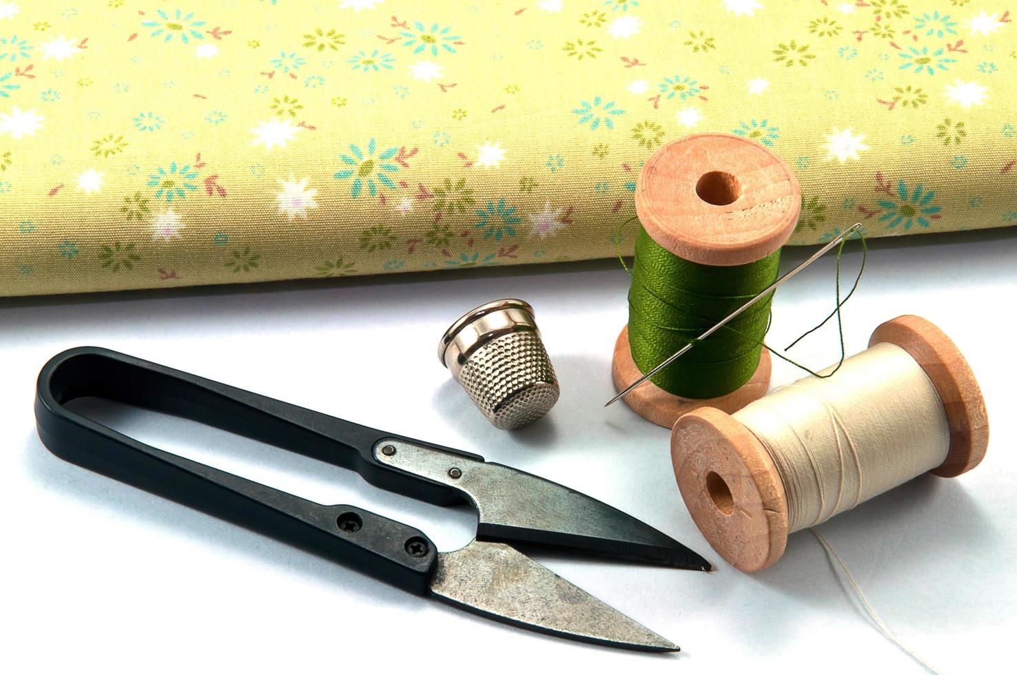 Thimble,needle,spools and scissor with cloth for sewing on white background photo