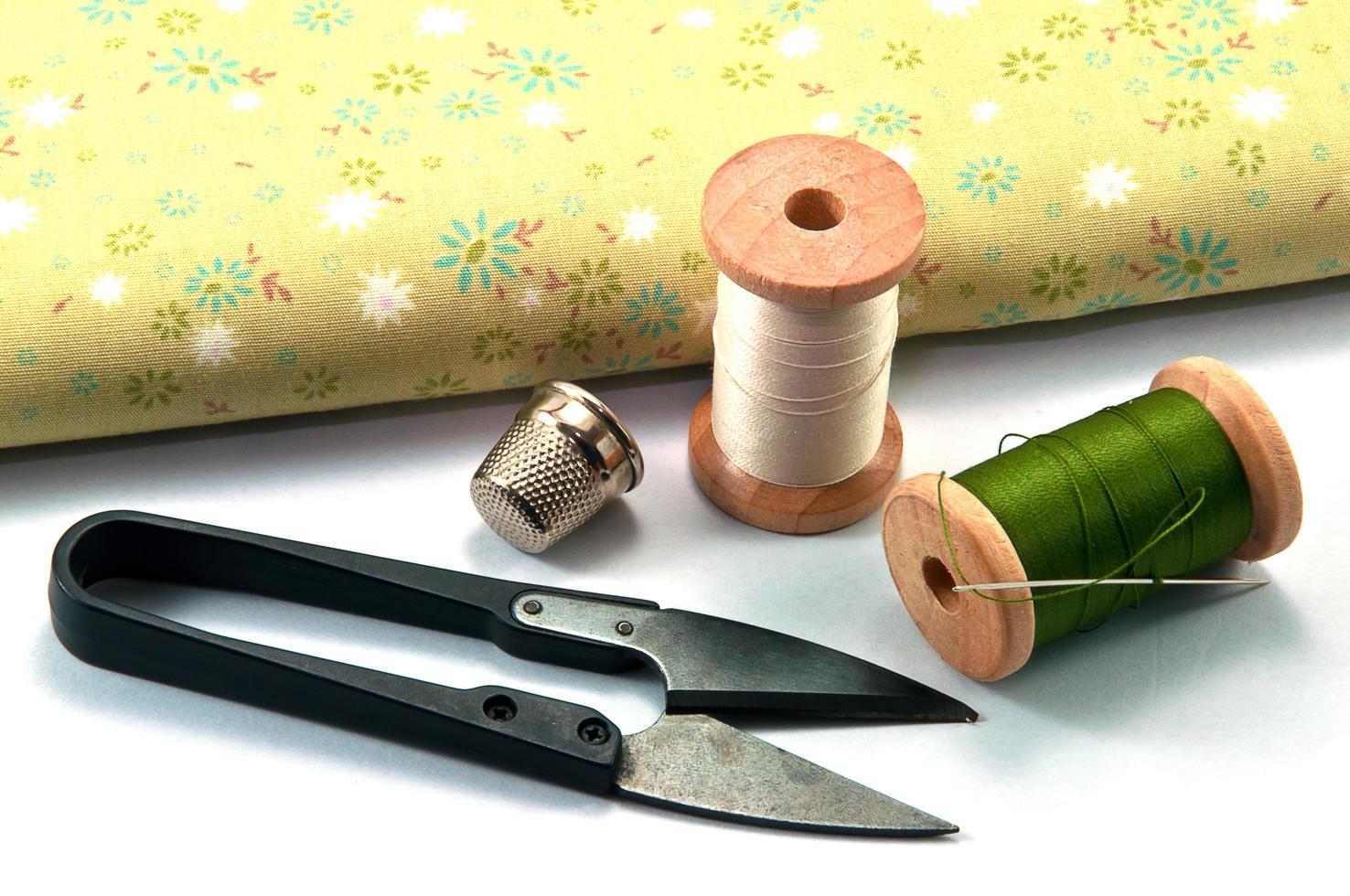 Thimble,needle,spools and scissor with cloth for sewing on white background photo