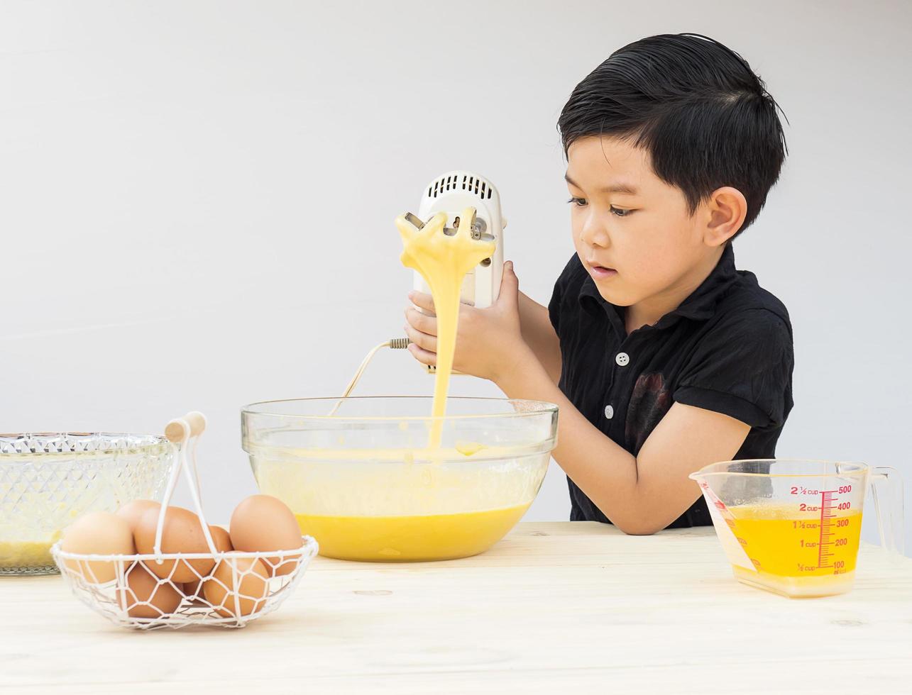 A boy is making cake. Photo is focused at his face.