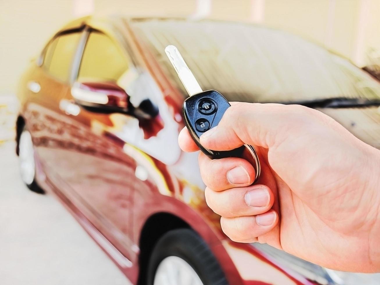 Man's hand is holding remote key pointing to his car photo