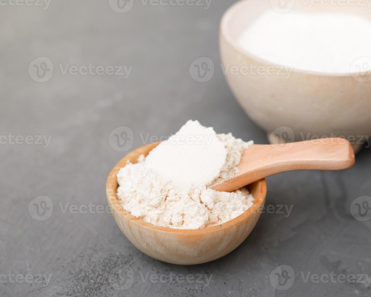 coconut flour in a wooden plate and a spoon. alternative flour for keto meal and LCHF diet. ingredient for healthy gluten free baking. photo