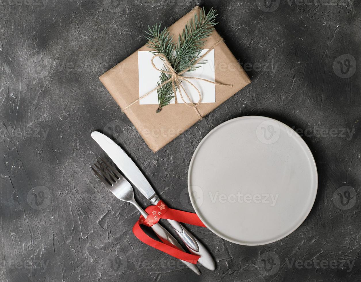 empty plate with tableware and christmas decor on grey table. copy space. table setting template for new year or christmas menu. restaurant menu mock up. top view photo