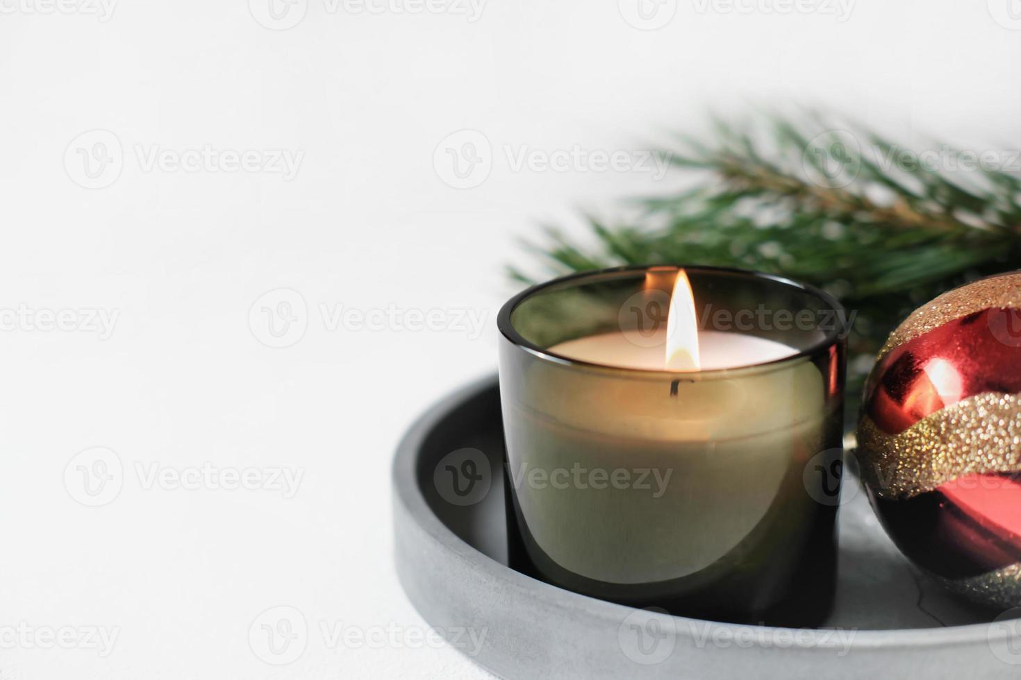 burning christmas green candle on a concrete tray next to new year decor. hcopy space, home scents for cozy atmosphere. photo