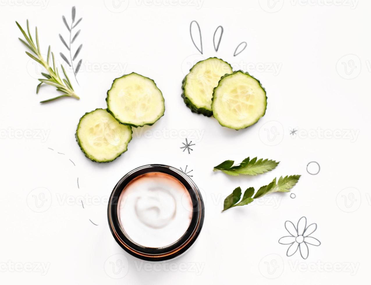 cucumber and rosemary face care mask on white background. natural organic cosmetics ingredients. cream in glass jar. top view photo