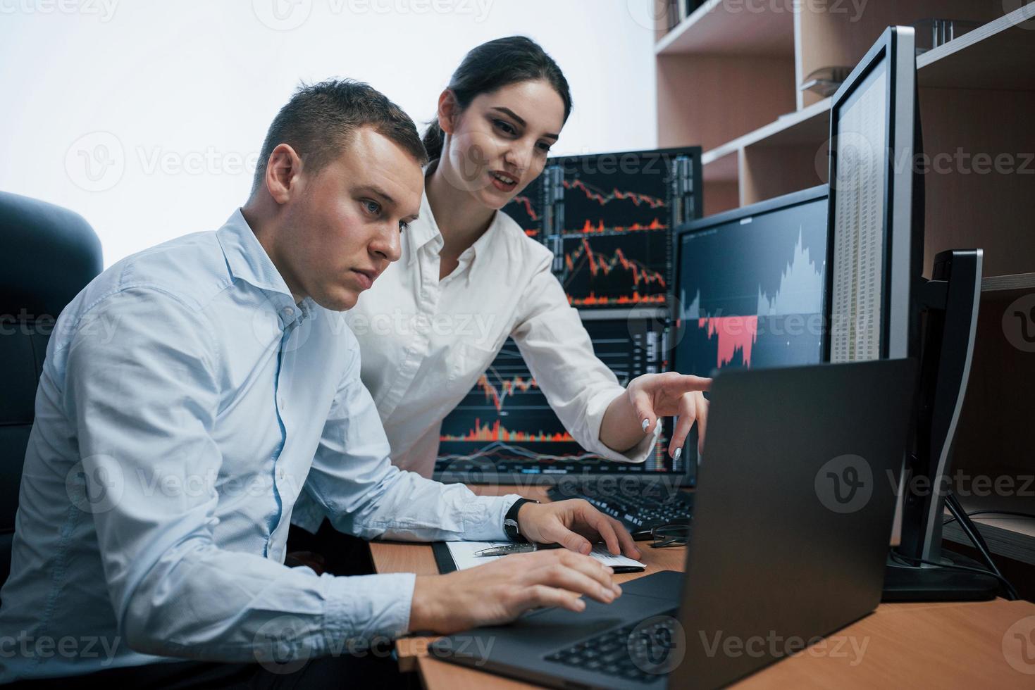 Creating new project. Team of stockbrokers are having a conversation in a office with multiple display screens photo