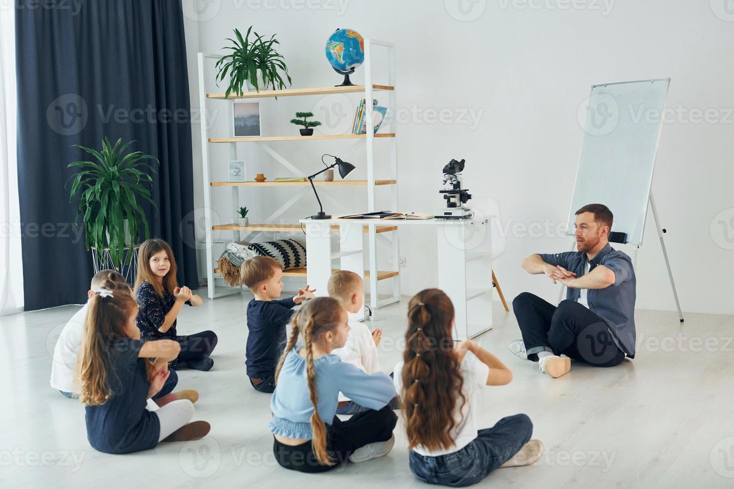 Man teaches gesture language. Group of children students in class at school with teacher photo