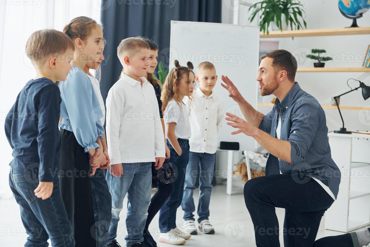 Storyteller with interesting information. Group of children students in class at school with teacher photo