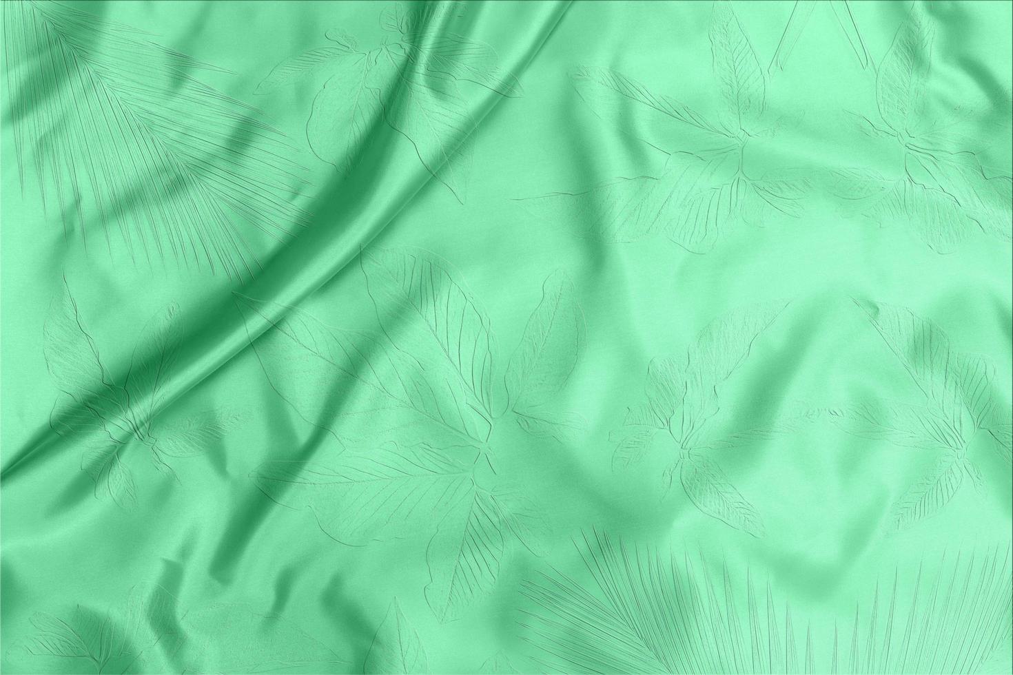 green satin fabric texture soft blur with palm leaves pattern background photo