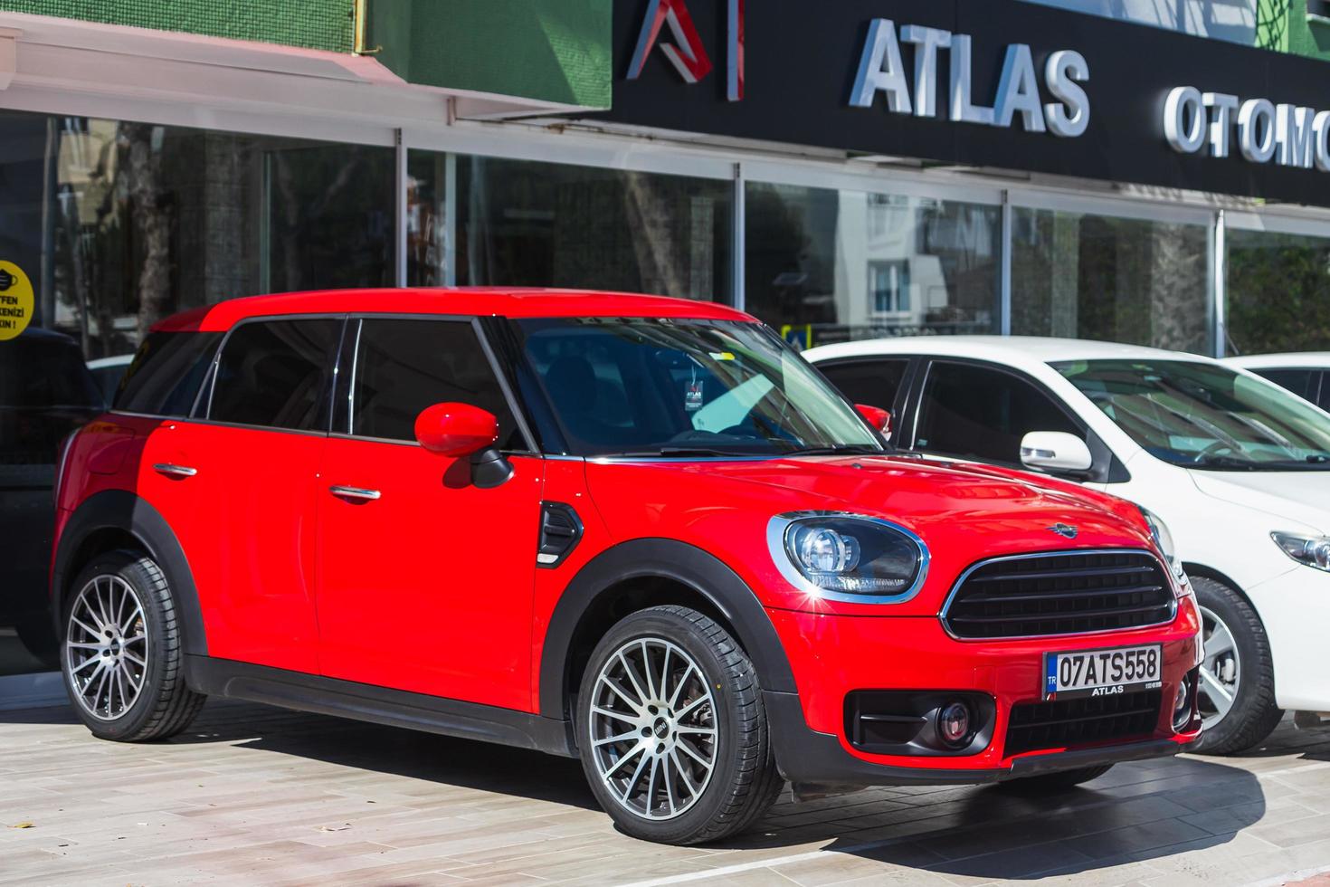 Antalya Turkey  March 04 2022 red Mini Countryman    is parked  on the street on a warm summer day against the backdrop of a buildung, trees photo