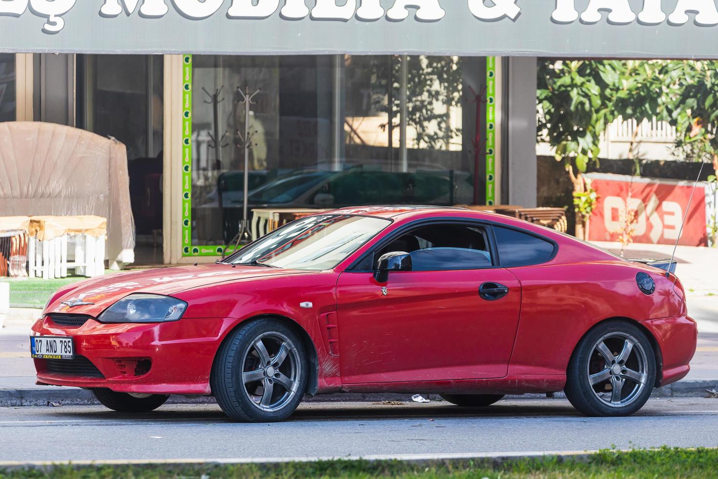 Antalya  Turkey March 04 2022  red Hyundai Tiburon  is parked  on the street on a warm day against the backdrop of a buildung,   shop photo