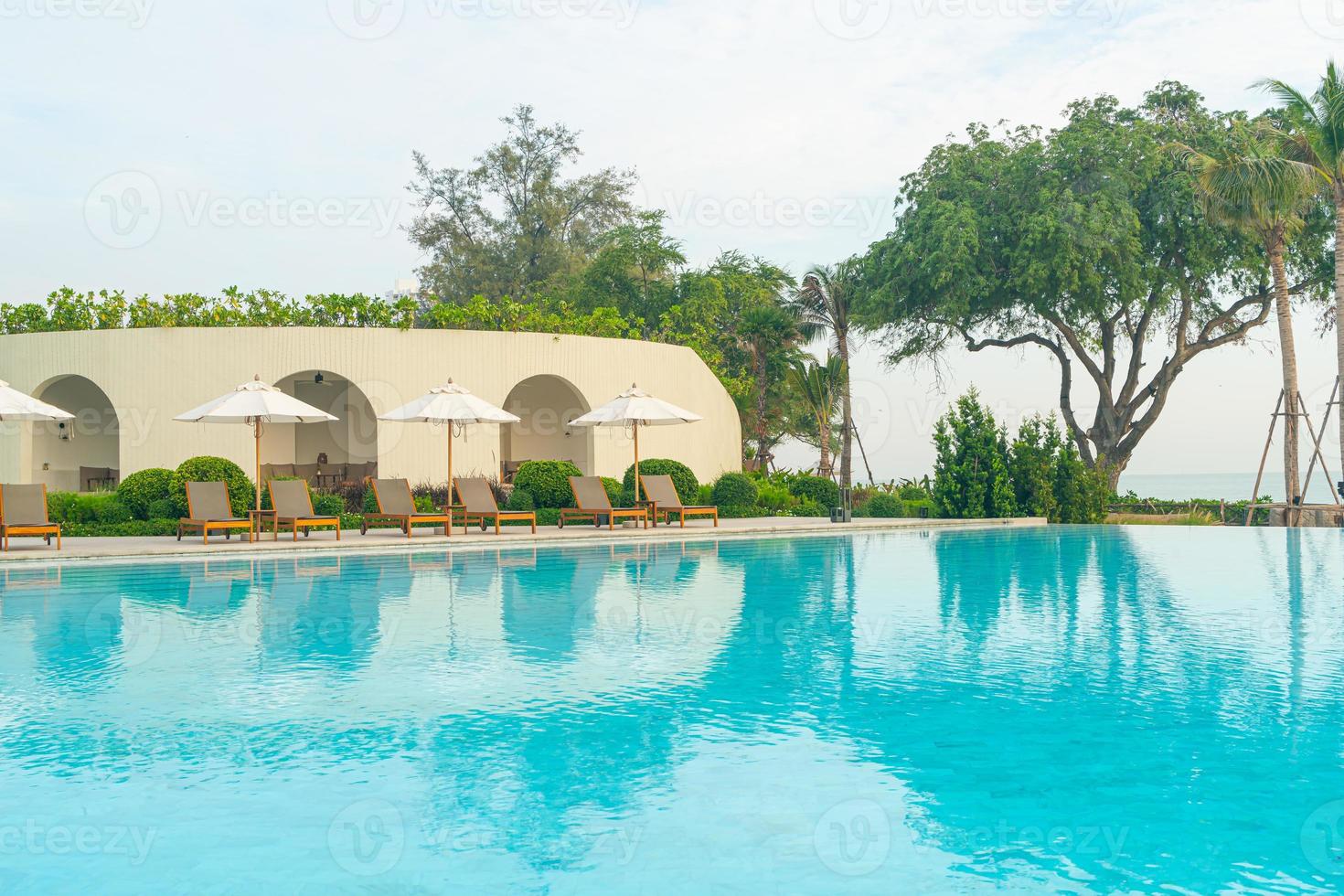 sombrilla con cama piscina alrededor de la piscina con fondo de mar océano foto