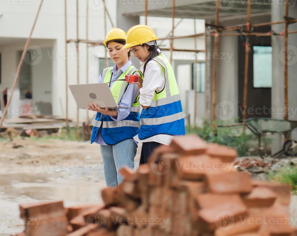 Construction workers are working, discussing, planning residential building blueprints at construction site. Real estate development project with civil engineer or investor team using laptop computer. photo