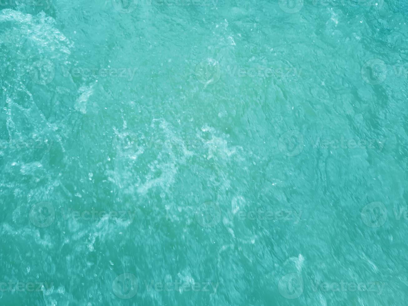 Defocus blurred transparent blue colored clear calm water surface texture with splashes and bubbles. Trendy abstract nature background. Water waves in sunlight. Blue water background. photo