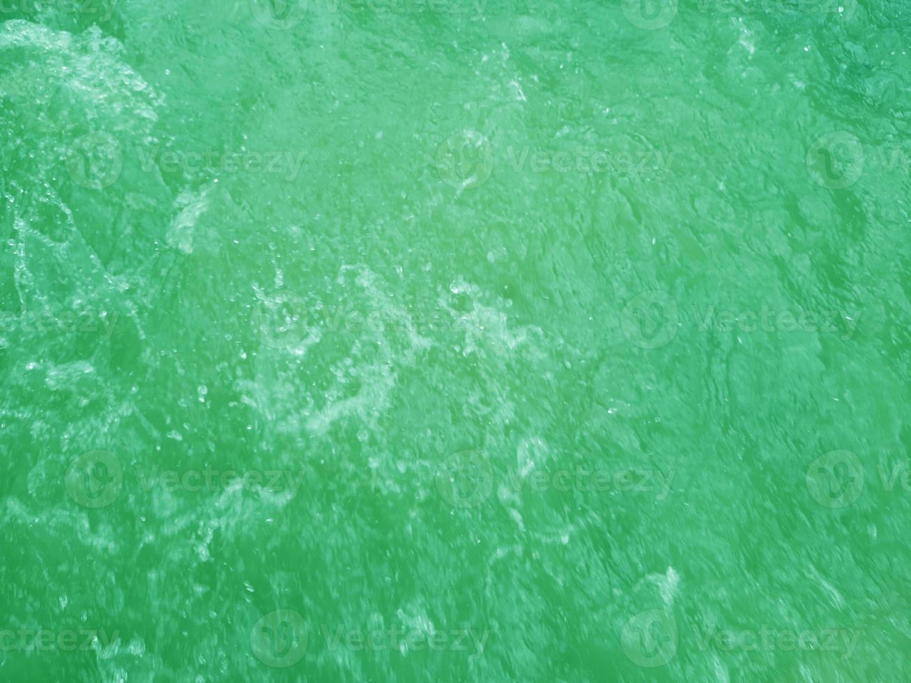 Defocus blurred transparent green colored clear calm water surface texture with splashes and bubbles. Trendy abstract nature background. Water waves in sunlight. Green water background. photo