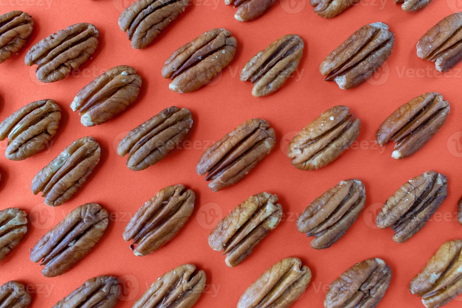 pecan halves arranged in pattern on fall orange background flat lay photo