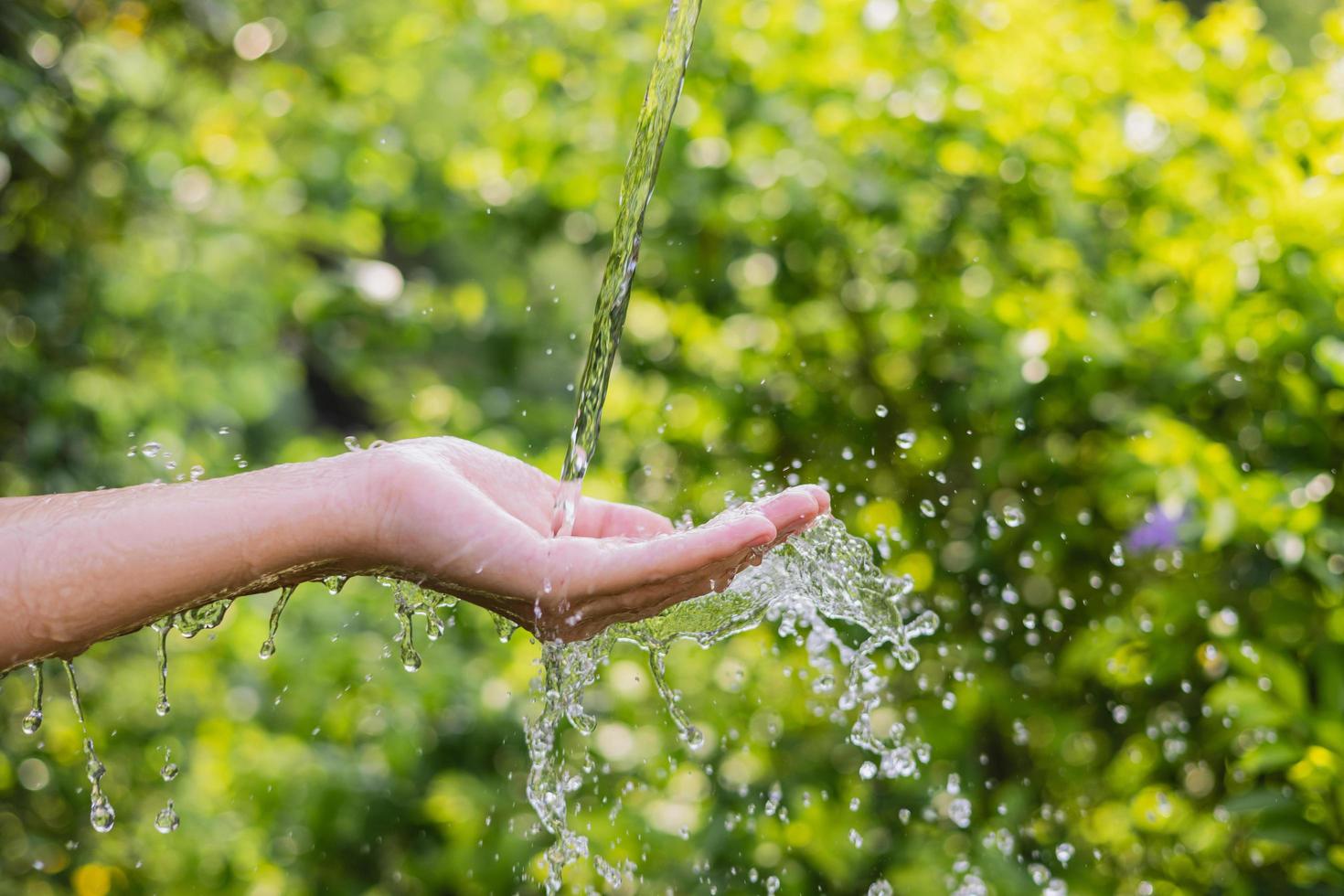 verter agua en la mano en el fondo de la luz de la mañana foto