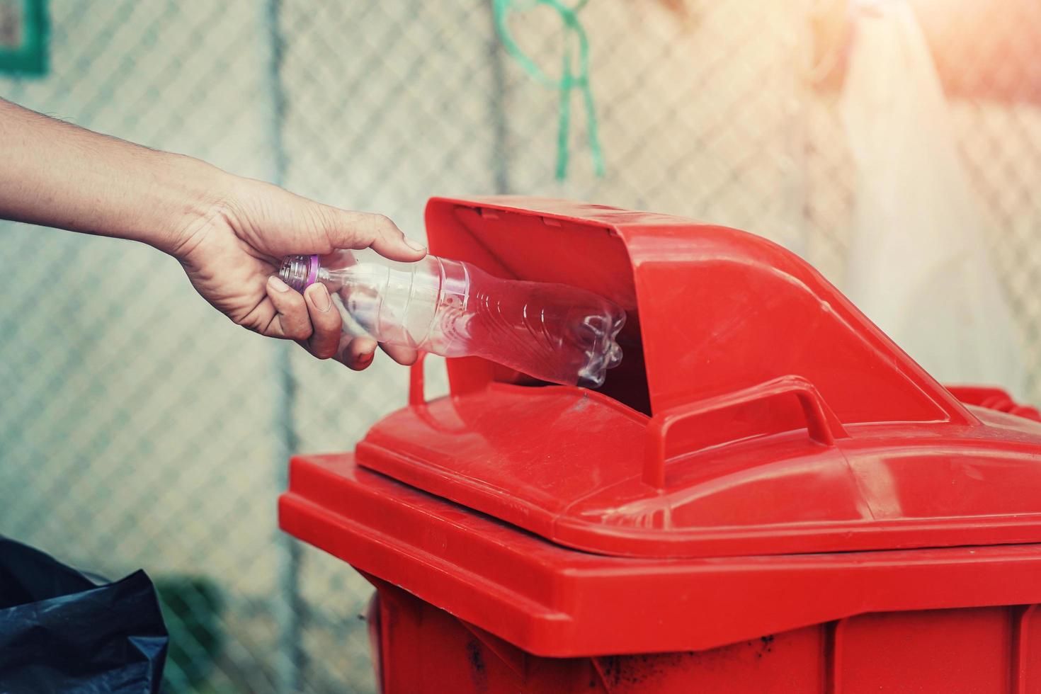 mano de personas sosteniendo una botella de basura de plástico poniendo en la papelera de reciclaje para limpiar foto