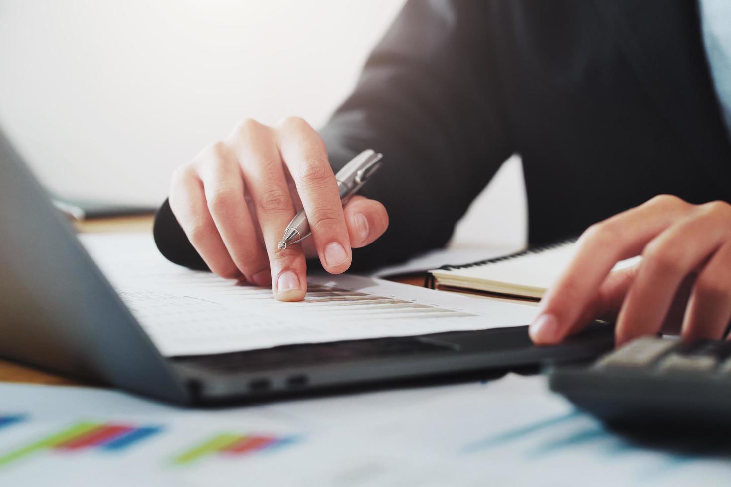close-up hand of businessman analyzing investment chart on paperwork with laptop in office. concept finance and accounting photo