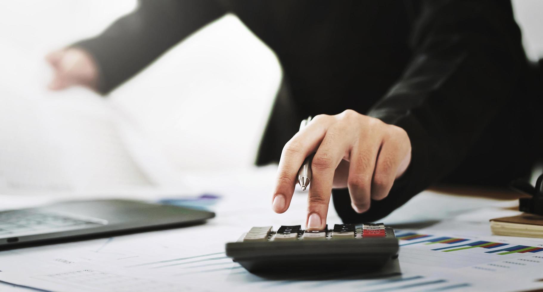 business accounting finance concept. accountant using calculator for calculate  with laptop working in office photo